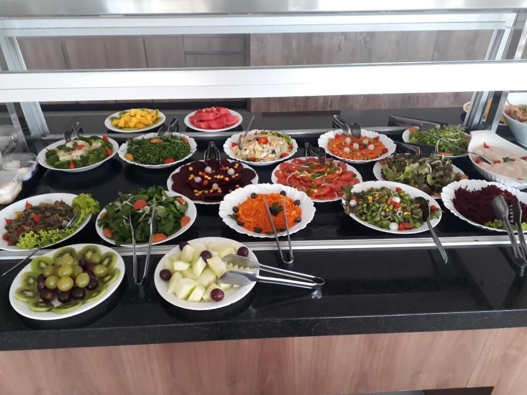 A buffet with various dishes including salads, fruits, and vegetables.