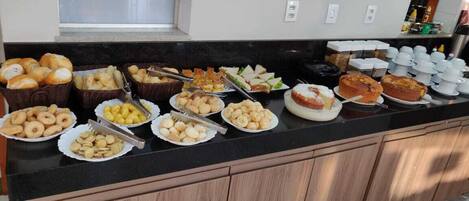 A buffet with various food items including pastries, sandwiches, and a pie.