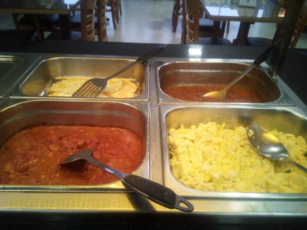En buffé med ett varierat utbud av mat, inklusive pasta, ris och en röd sås.