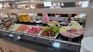 A buffet with various food items including fruits, cheeses, and meats.