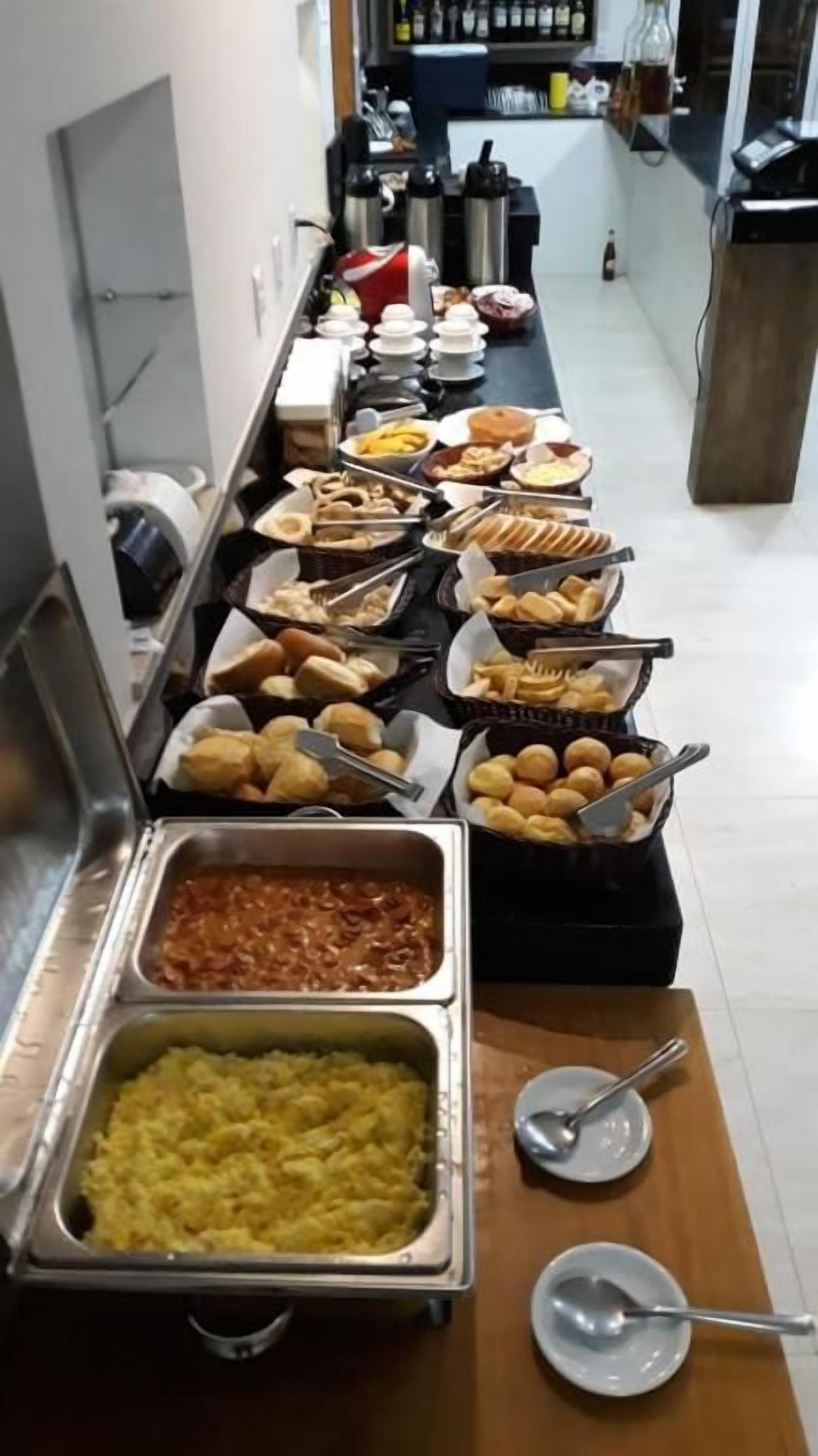 Buffet com diversos alimentos, incluindo massa, pão e sobremesas.