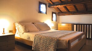 A bedroom with a wooden bed, bedside tables, a nightstand, and a window with curtains.
