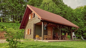 A rustic wooden cabin with a porch, a chimney, and a small outdoor seating area.