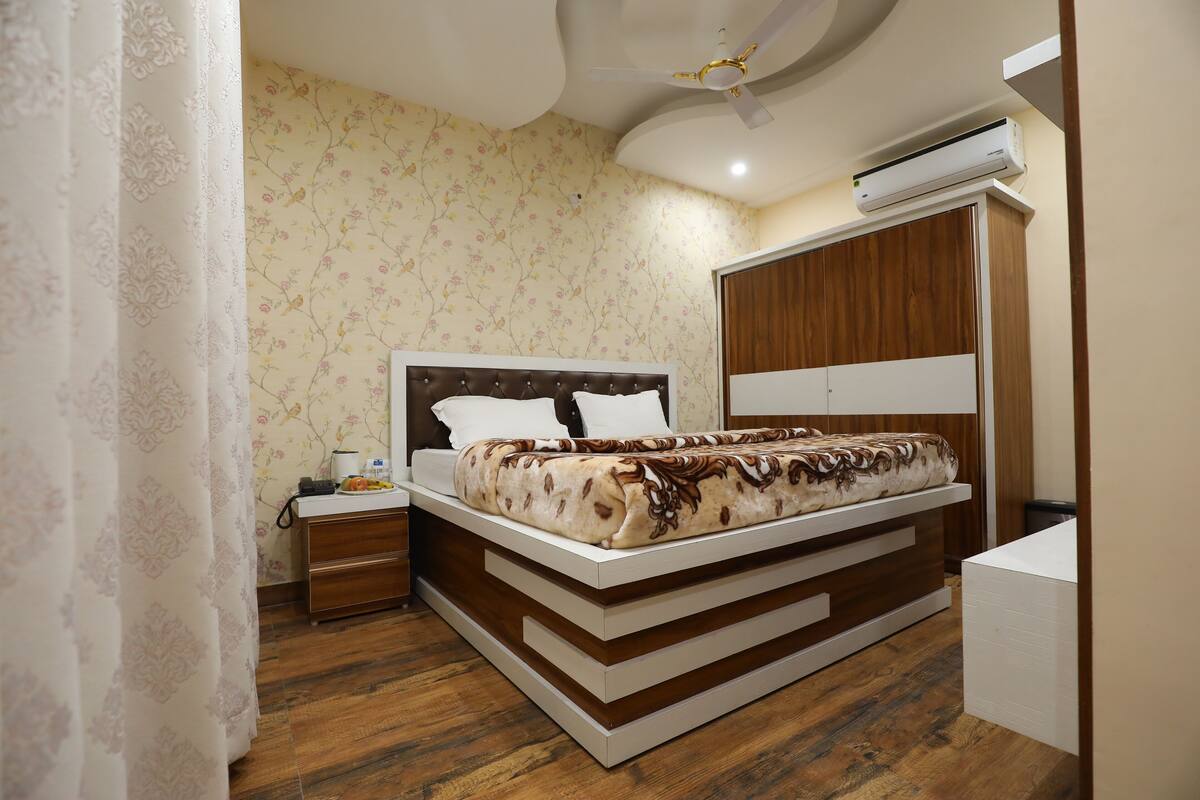 A bedroom with a bed, nightstand, wardrobe, and an air conditioning unit.