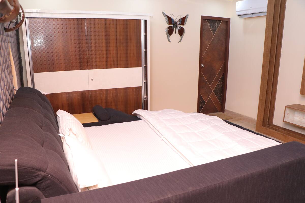 A bedroom with a bed, a sofa, a wardrobe, and a butterfly decoration on the wall.