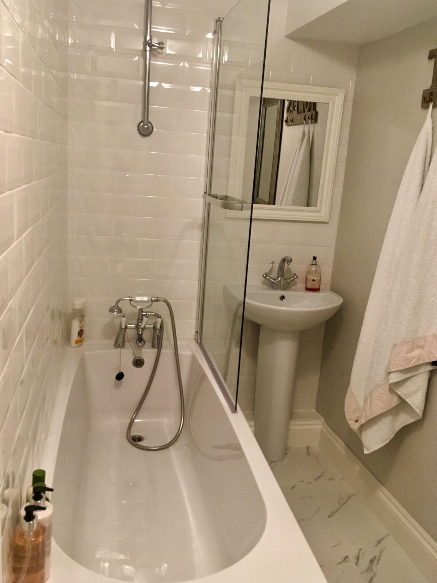 A bathroom with a glass-enclosed shower, a sink, and a mirror.