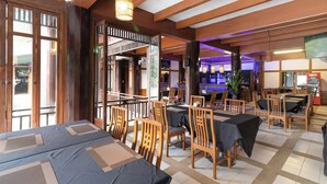 Een restaurant met houten meubels, tafels, stoelen en een bar met krukken.