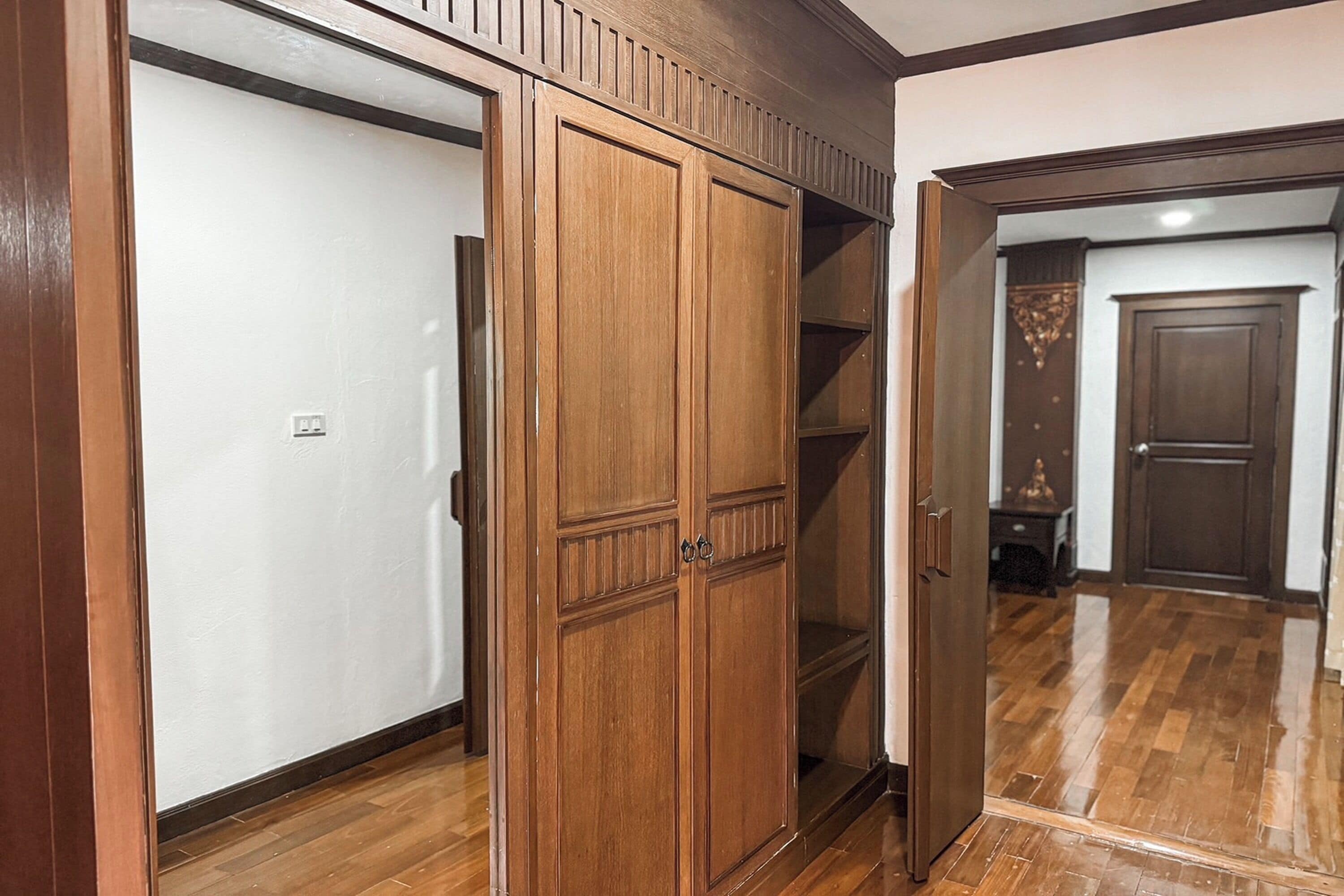A hallway with wooden flooring and a wooden wardrobe with a mirrored door.