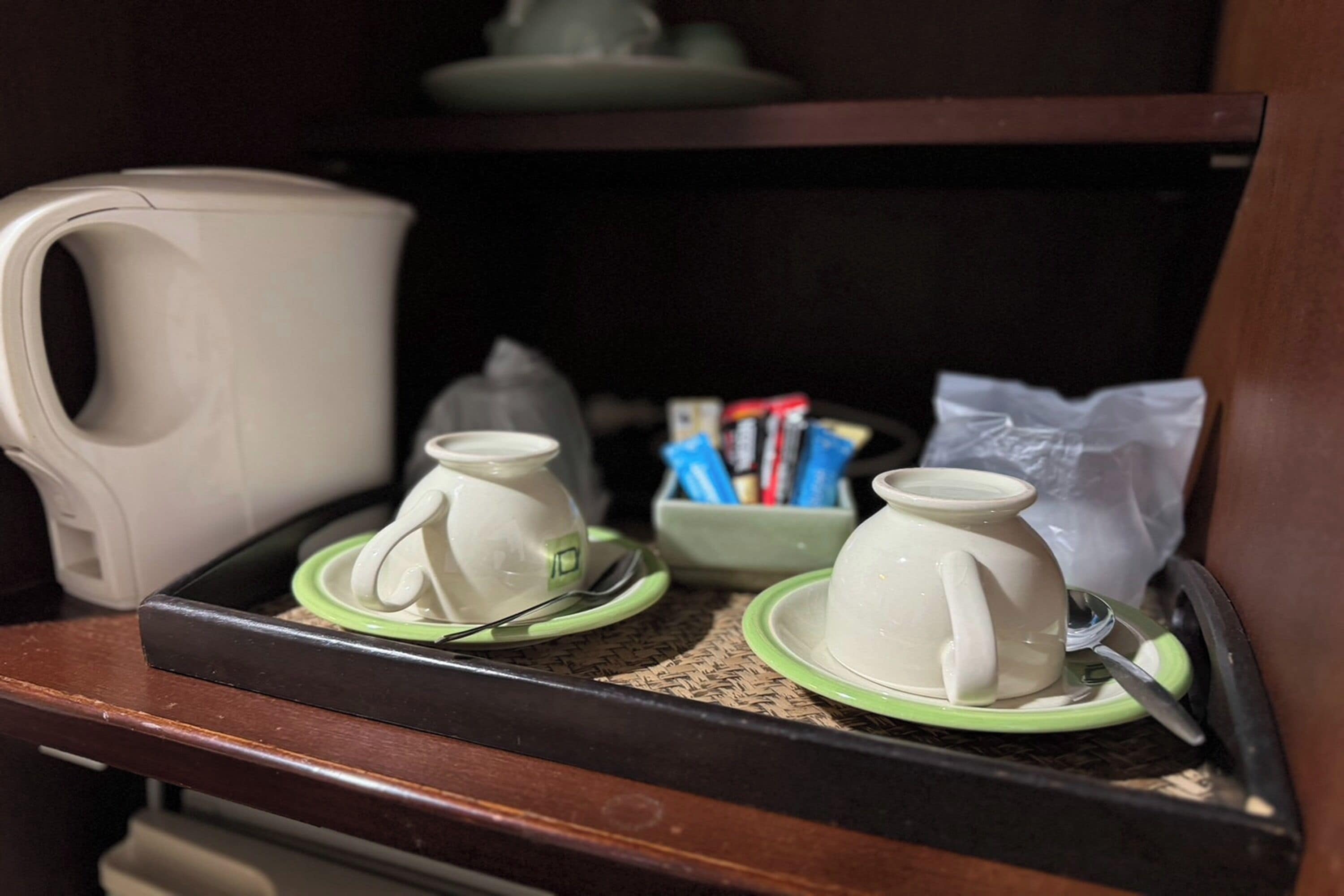 A tray with a white coffee pot, two white teapots, and a green tray liner.