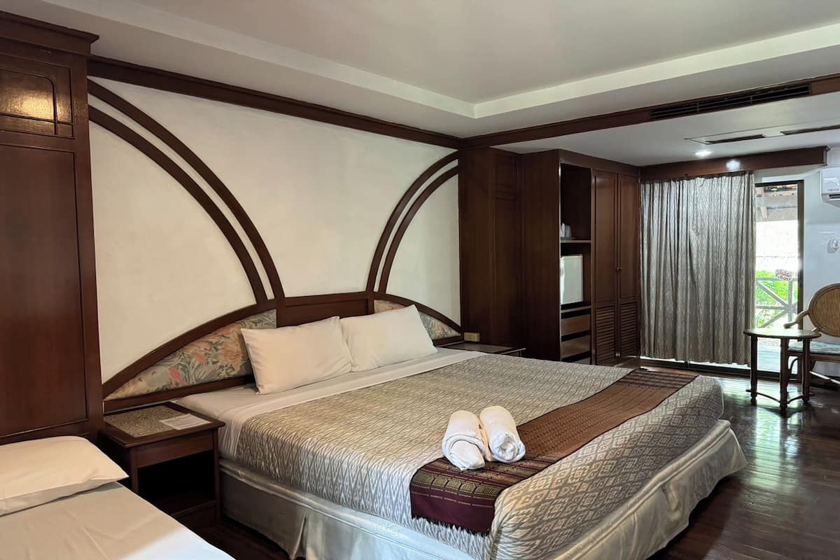 Une chambre d’hôtel avec un grand lit, une tête de lit en bois et une vue sur l’extérieur par une fenêtre.