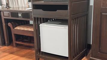 Geladeira compacta em cozinha com armários de madeira e uma cadeira.
