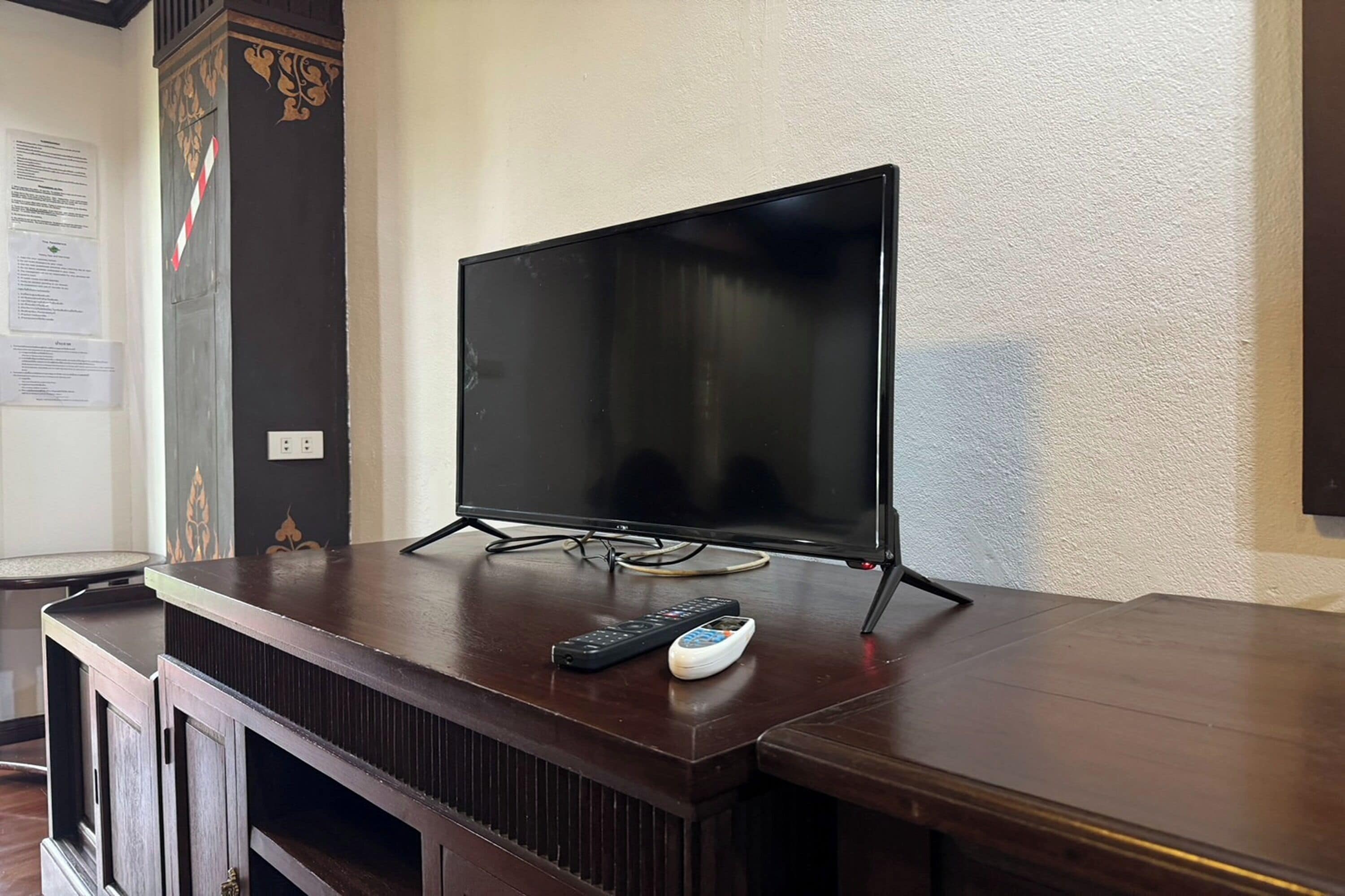 Un televisor sobre un soporte de madera con un control remoto y un ratón al lado.