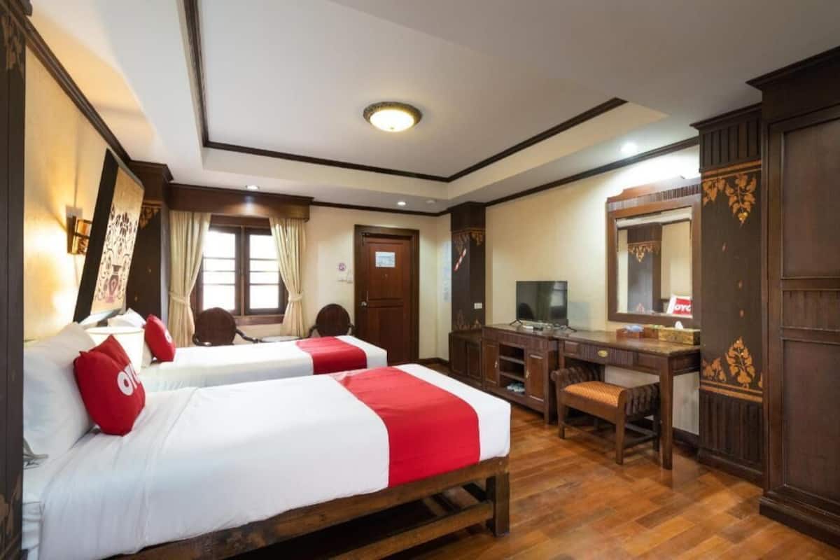 Une chambre d’hôtel avec deux lits, un bureau, une chaise, une télévision et une armoire.