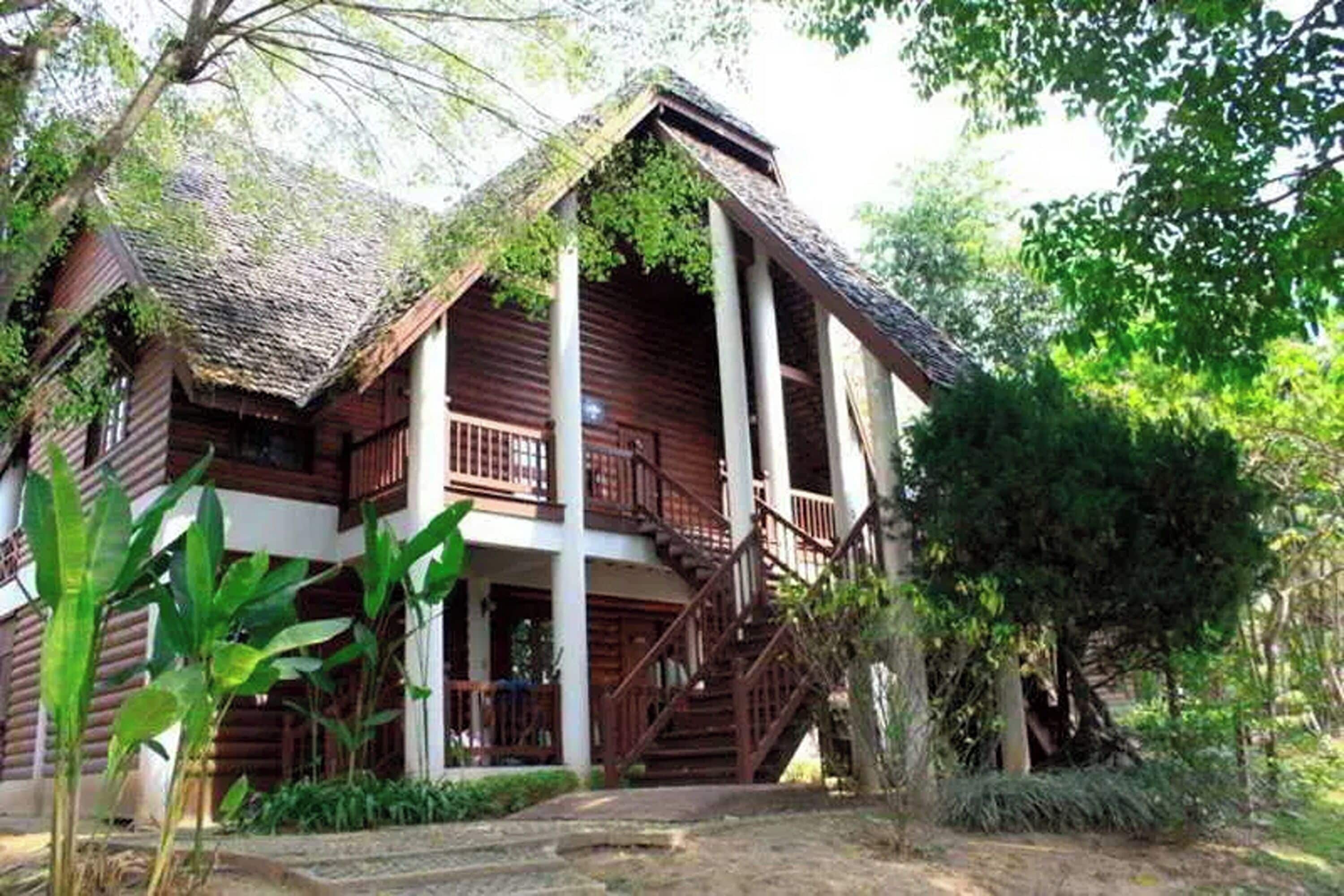 A wooden house with a balcony and a staircase leading to the entrance.
