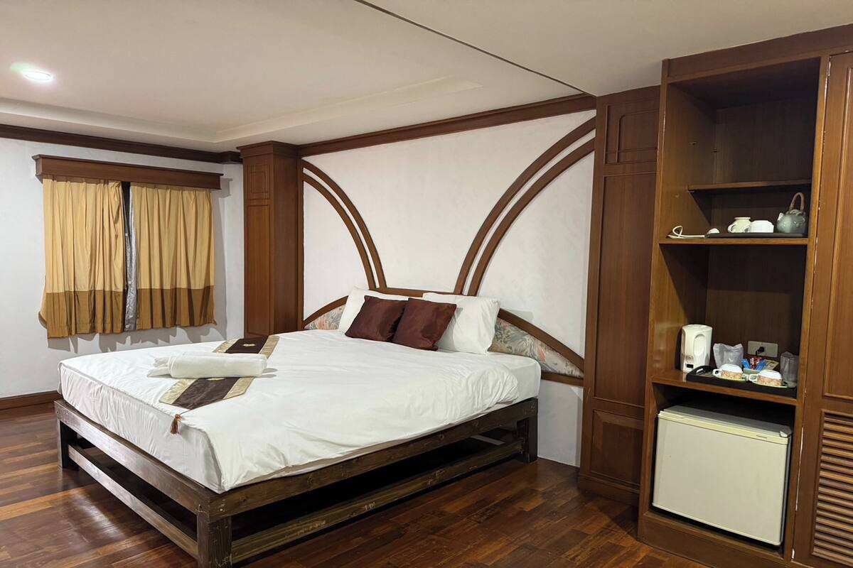 Une chambre avec un lit en bois, une armoire et un petit réfrigérateur.