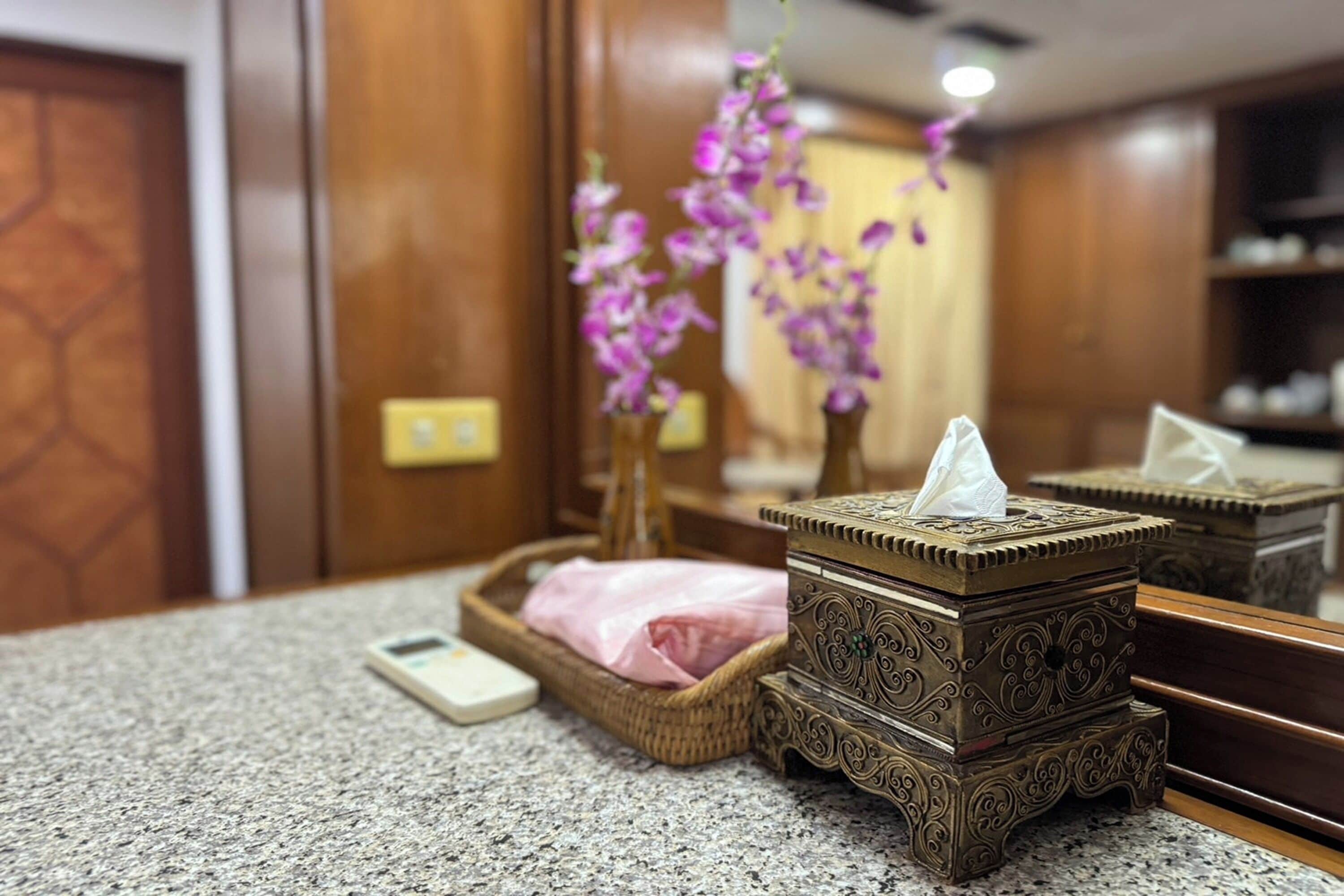 A bathroom vanity with a tissue box, a tissue dispenser, and a small potted orchid.