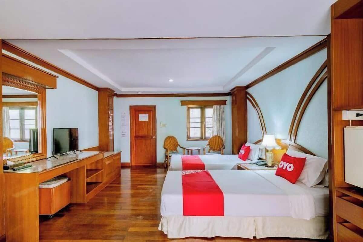 Une chambre d’hôtel avec deux lits, un bureau, une télévision et un miroir.