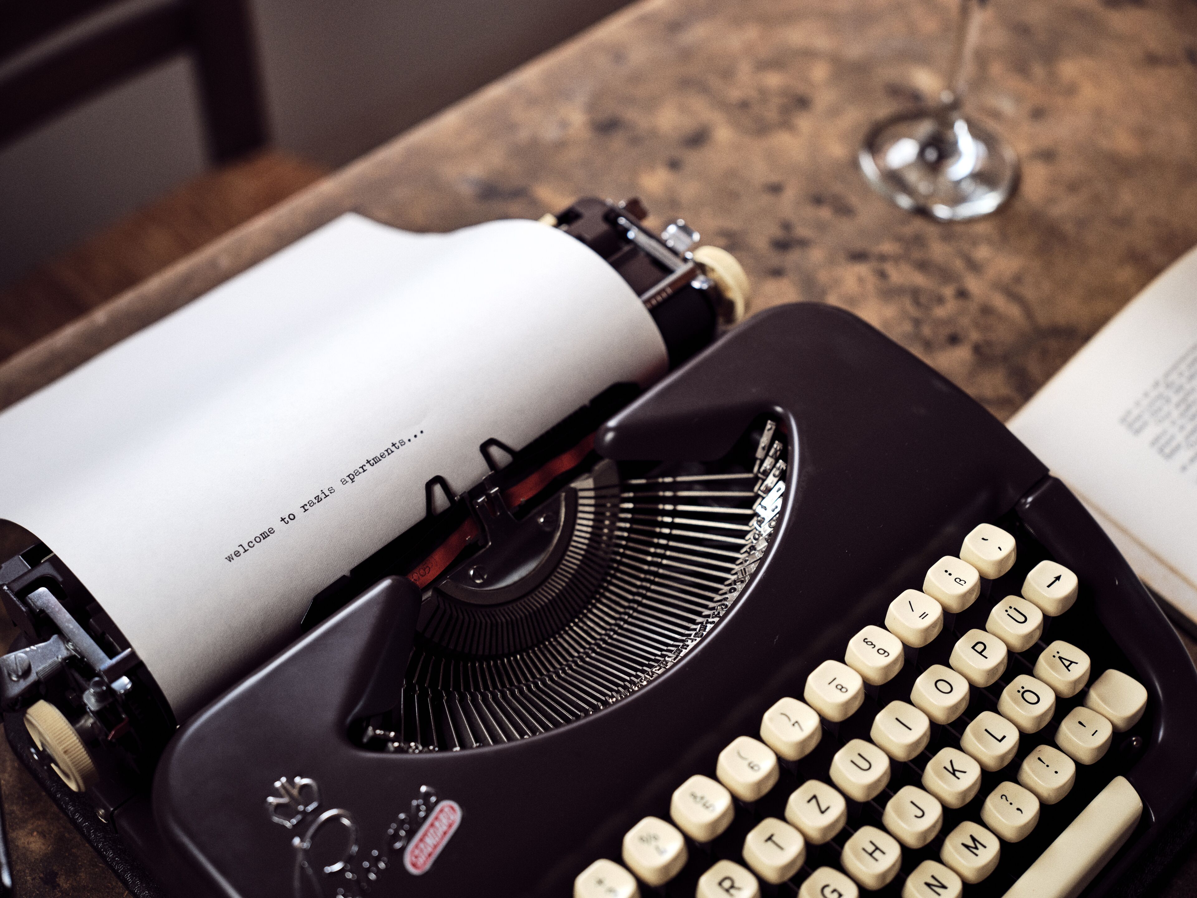 A vintage typewriter with a sheet of paper that reads "welcome to razis apartments..."