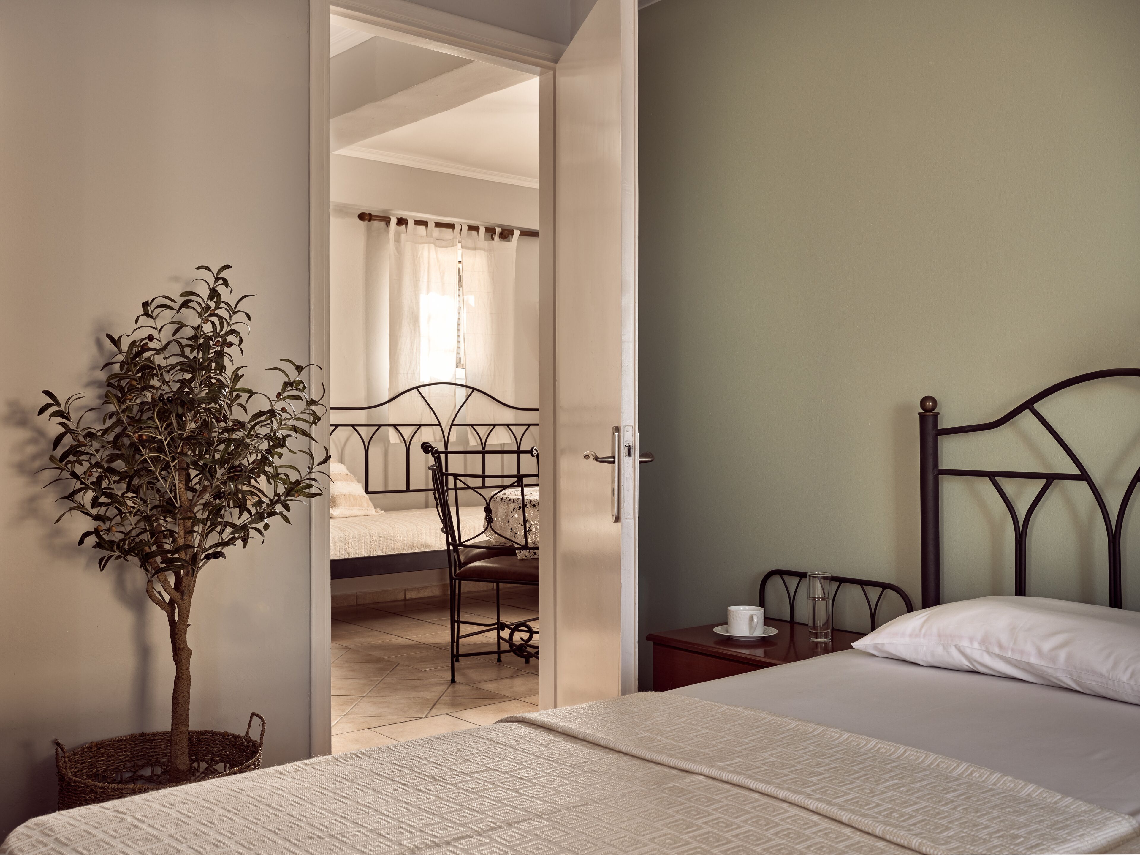 Un dormitorio con una cama, una mesita de noche, una silla y una planta en maceta.