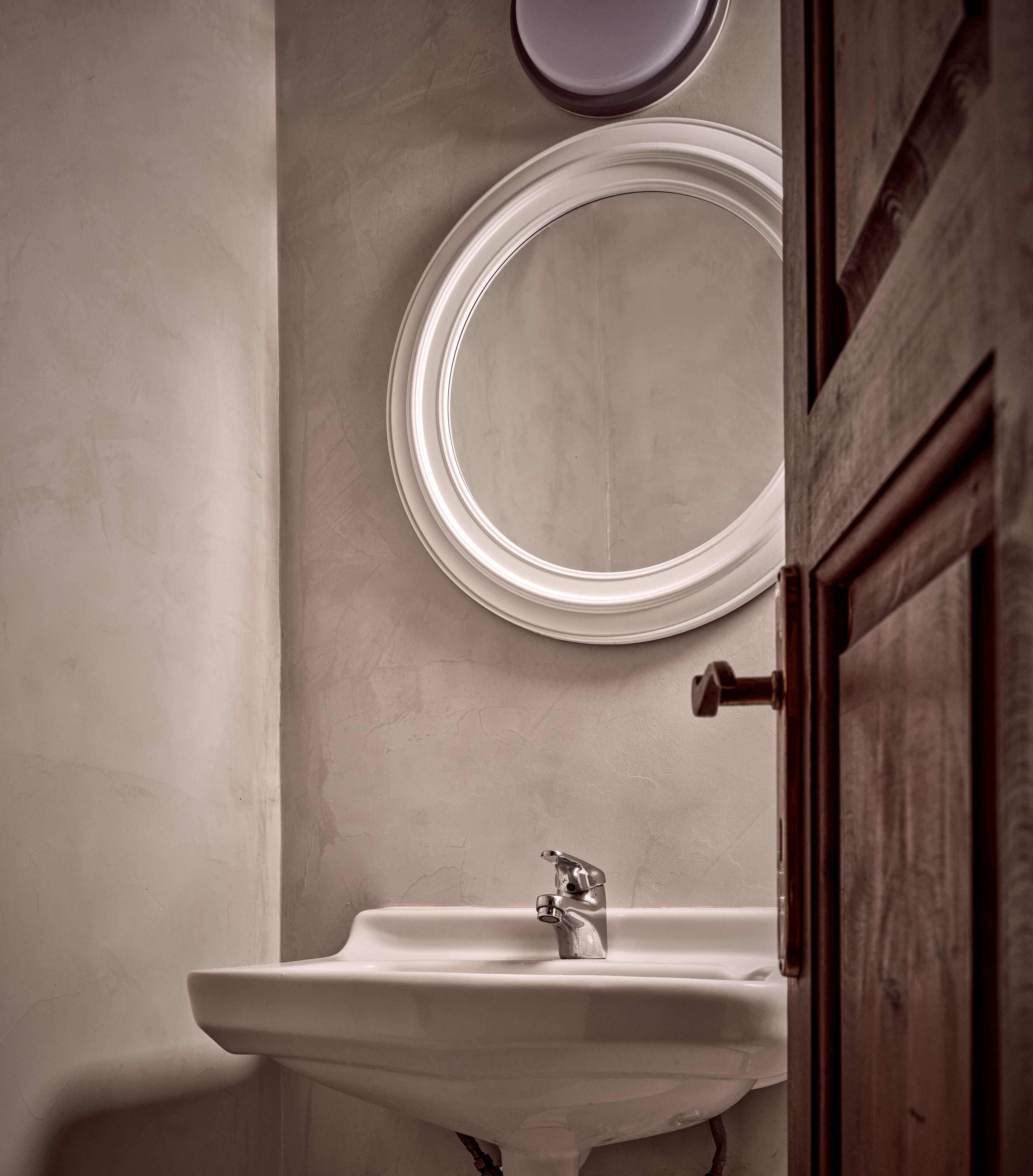 A bathroom with a sink, a mirror, and a door.