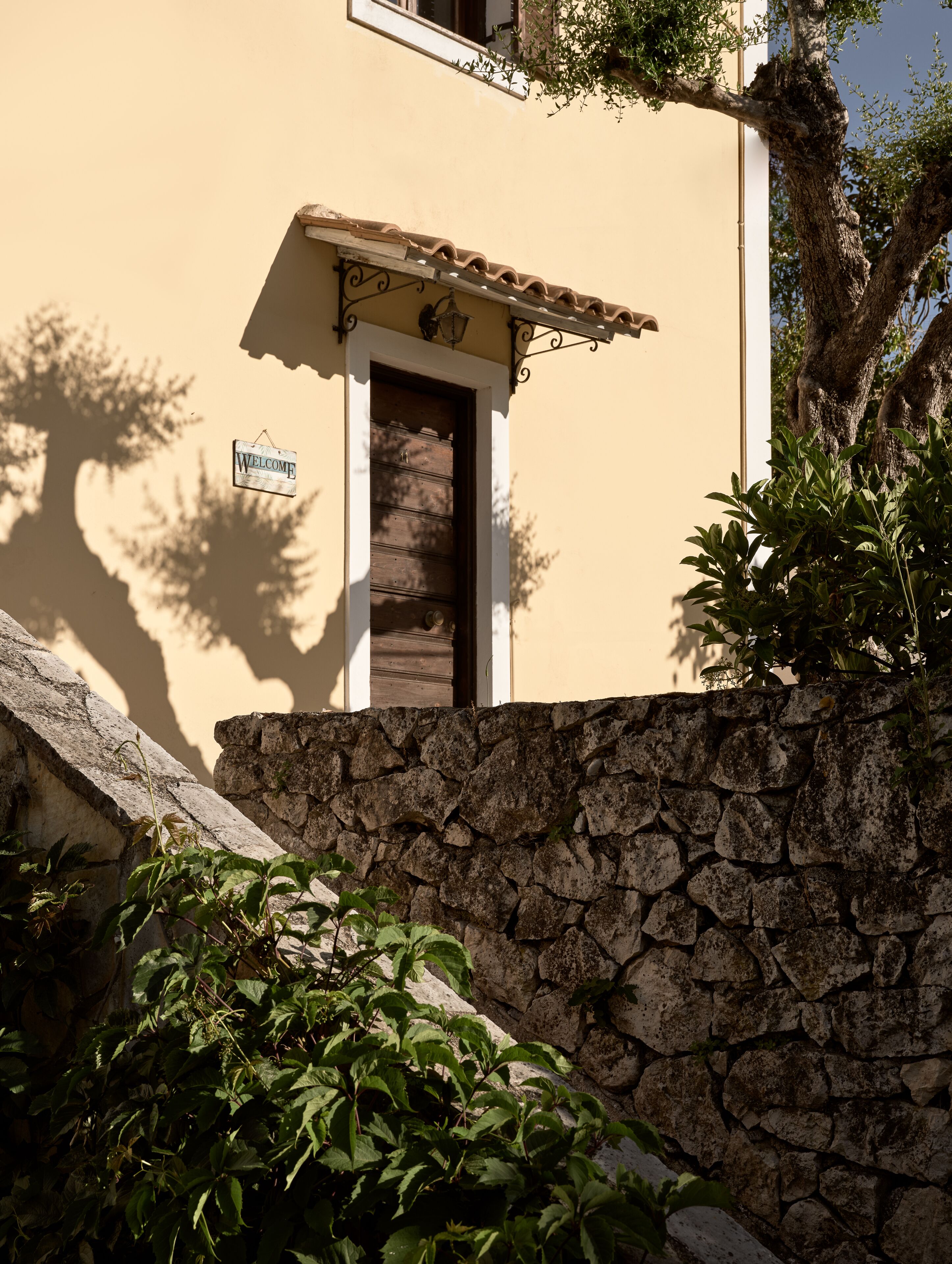 A stone wall with a wooden door and a 'Welcome' sign.