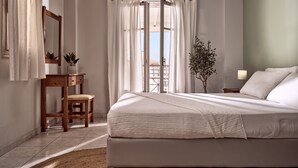 Une chambre à coucher avec un lit, un bureau, une chaise, une plante en pot et une vue sur l’extérieur.