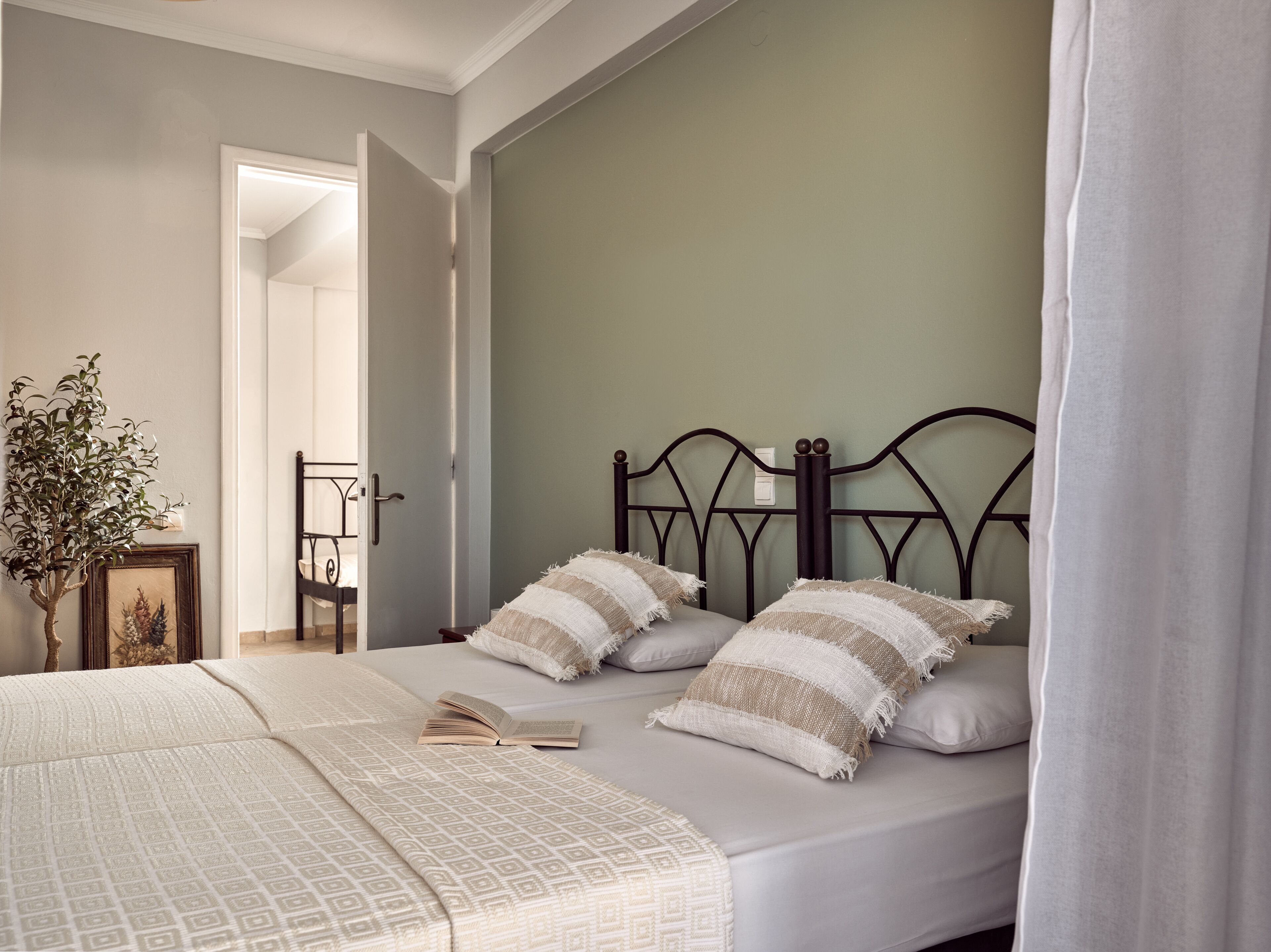 A neatly made bed with a patterned bedspread, two pillows, and an open book on the bed.