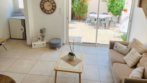 A modern living room with a sofa, a coffee table, a clock, and a view of the outside patio. - Villa with terrace 200m from the beach (Six-Fours-les-Plages)