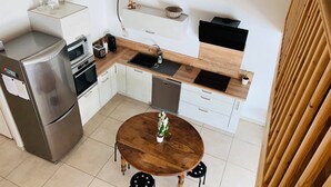 A compact kitchen with a refrigerator, oven, and sink. There is a wooden dining table with chairs. - Villa with terrace 200m from the beach (Six-Fours-les-Plages)