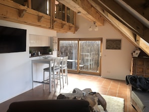 A modern kitchen with white cabinets, a dining area with a white table and chairs, and a large sliding glass door leading to an outdoor area.