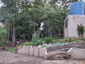 A garden with a water tank, stone steps, and various plants.