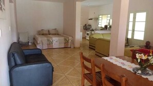 Una sala de estar con un sofá, una mesa de comedor con sillas y una cocina al fondo.