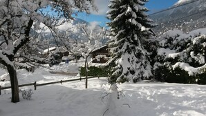 Un paysage enneigé avec une clôture en bois, un bonhomme de neige et une maison en arrière-plan.