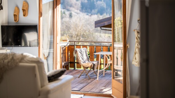 Une pièce chaleureuse avec une terrasse en bois, une chaise et une table.