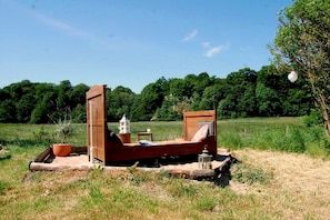 Un lit d’extérieur rustique, doté d’une structure en bois, d’une lanterne et d’une petite table.