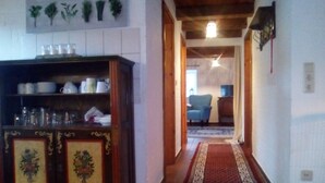 Un couloir avec une armoire en bois, une moquette rouge et un fauteuil bleu à l’arrière-plan.