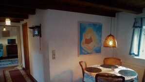 Un coin repas comprenant une table ronde, quatre chaises, un tableau au mur et une lampe suspendue.