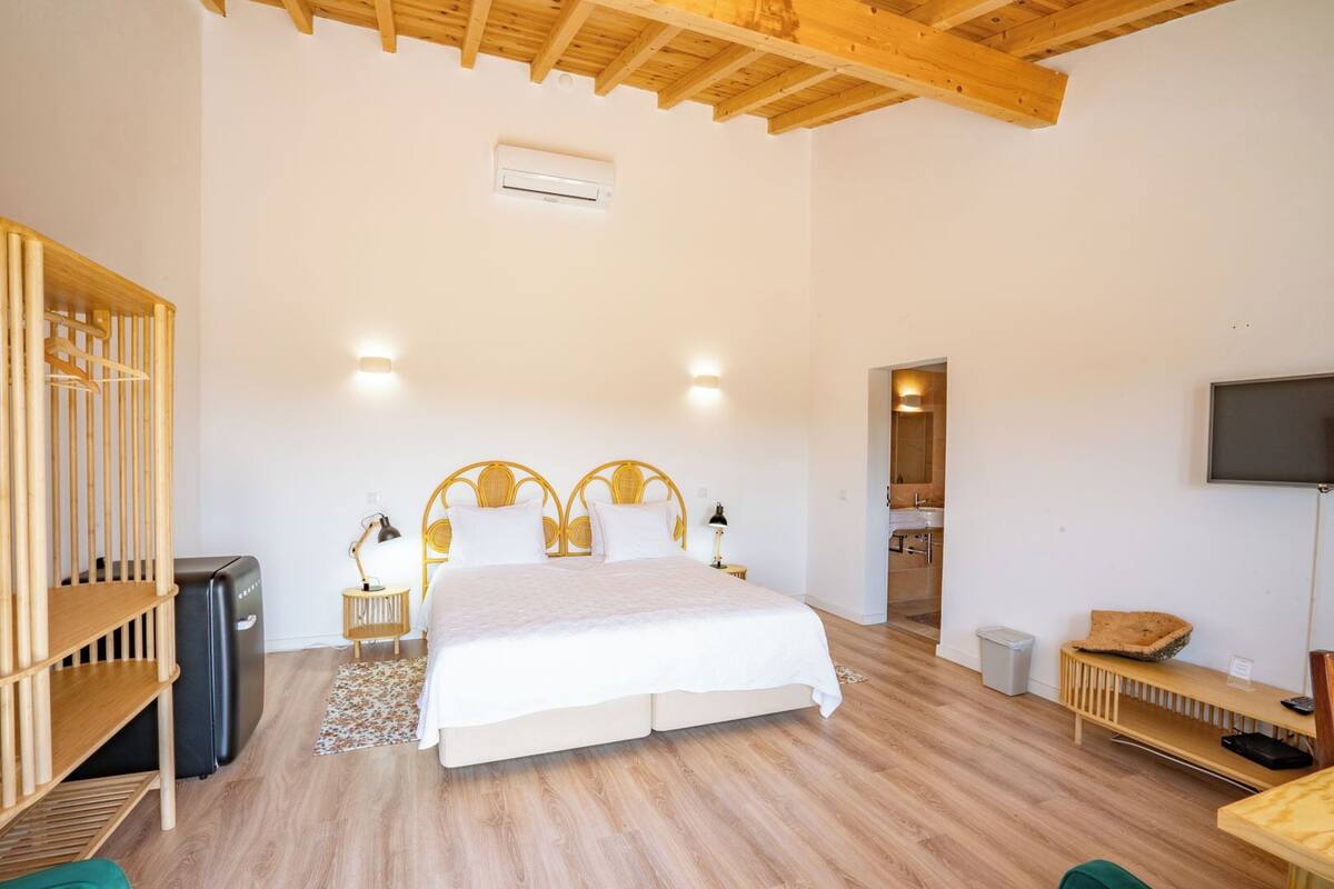 A bedroom with a bed, bedside tables, a TV, and a wooden wardrobe.