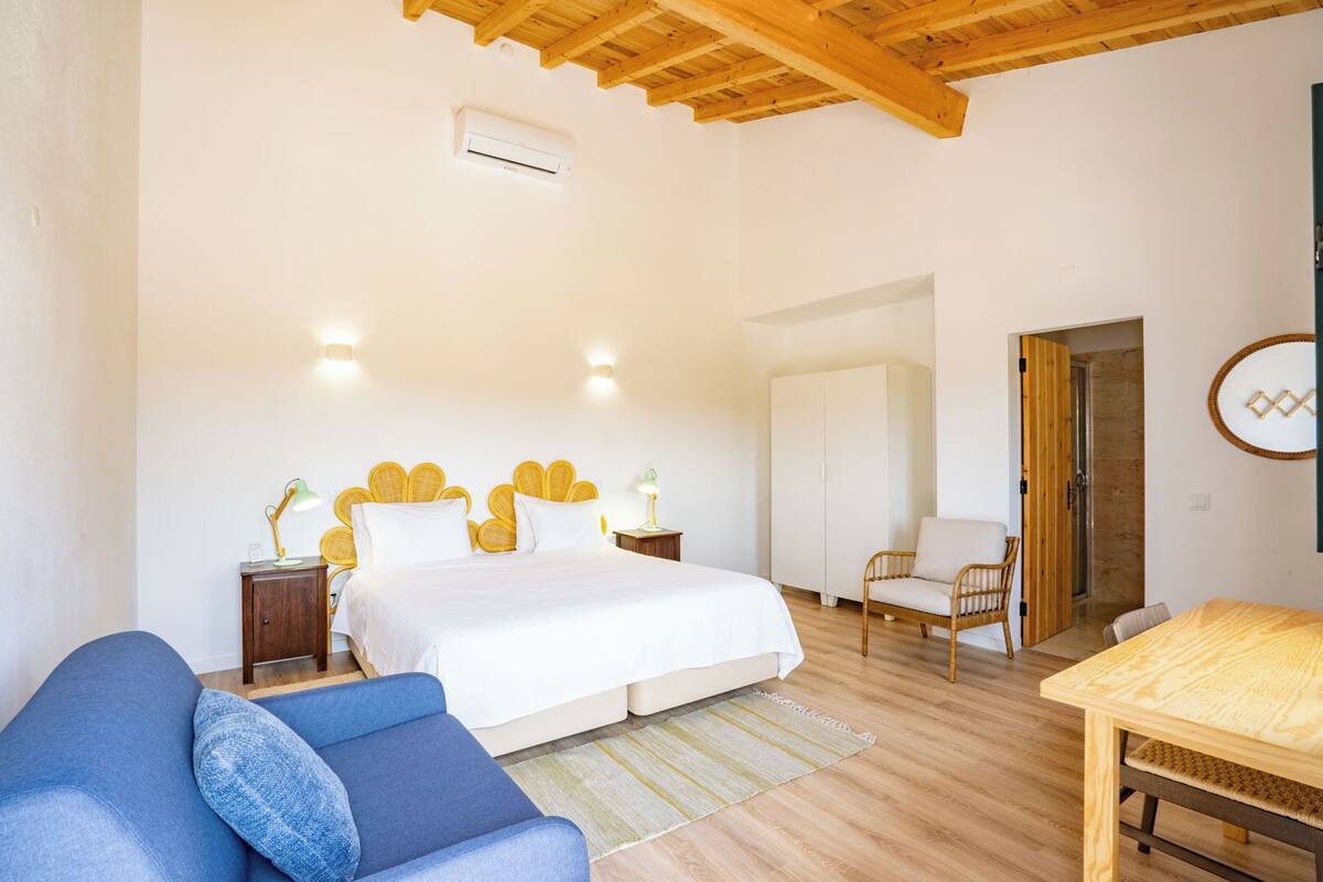 A bedroom with a bed, a chair, a table, and a wardrobe.