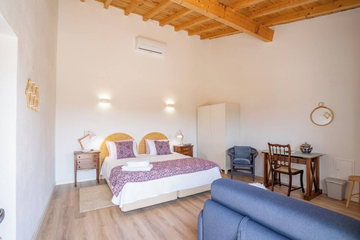 A bedroom with a bed, bedside tables, a wardrobe, a desk with a chair, and a blue sofa.