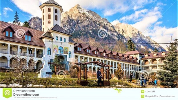 A hotel with a central tower, multiple balconies, and a mountainous backdrop. - Hotel House Bran (Busteni)