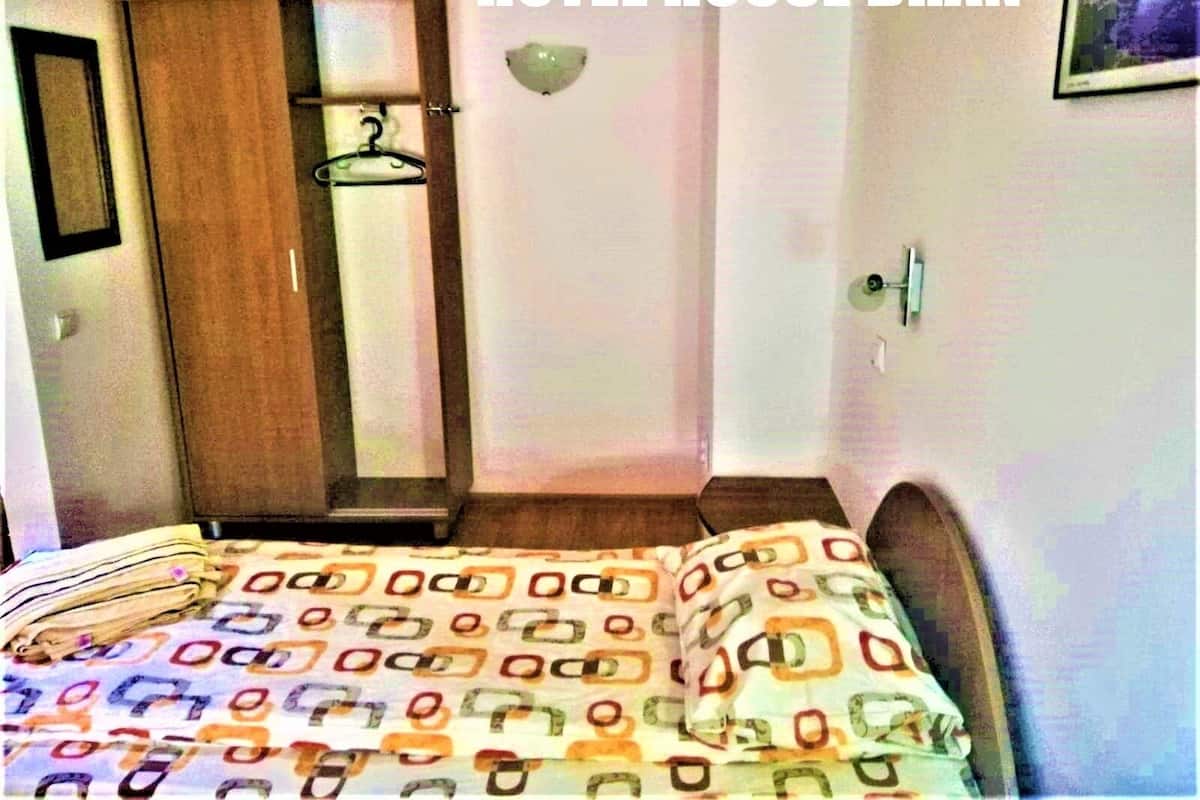 A hotel room with a bed, a wardrobe, and a mirror.