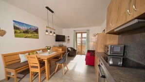 Eine moderne Küche mit Holzausbau, einer integrierten Mikrowelle und einem Essbereich mit Holztisch und Stühlen.