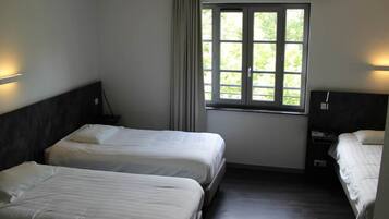 Una habitación de hotel con dos camas, una ventana con cortinas y una mesita de noche.