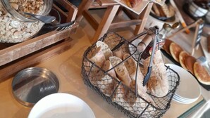 A buffet with various food items including bread, pastries, and a bowl of cereal. - Hotel Restaurant Le Tout Va Bien (Valence)