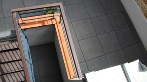 A corner of a room with a tiled floor and a metal gate. - Hotel Restaurant Le Tout Va Bien (Valence)