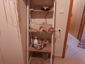A bathroom with a towel rack, a bottle of champagne, and a small trash bin.