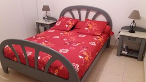 Un lit recouvert d’une couvre-lit à motifs floraux, deux tables de chevet avec des lampes et une chaise.