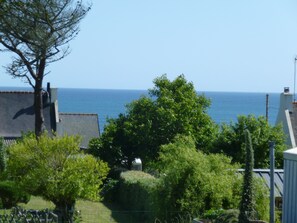 Une vue sur la côte, avec un ciel dégagé, un arbre et un bâtiment doté d’un toit en pente.