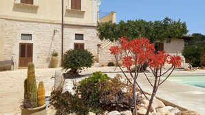 Un bâtiment en pierre doté d’une piscine, entouré de rochers et de plantes.